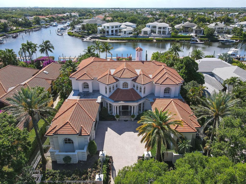 Outstanding custom estate located at 456 Mariner Dr, Jupiter, Florida, in the exclusive guard-gated community of Admirals Cove. It sits on 110' of waterfrontage with no fixed bridges. This timeless masterpiece features 5 BR/5.1 BA + an office, boasting 9,101 sq ft with soaring ceilings and spectacular water views from almost every room.