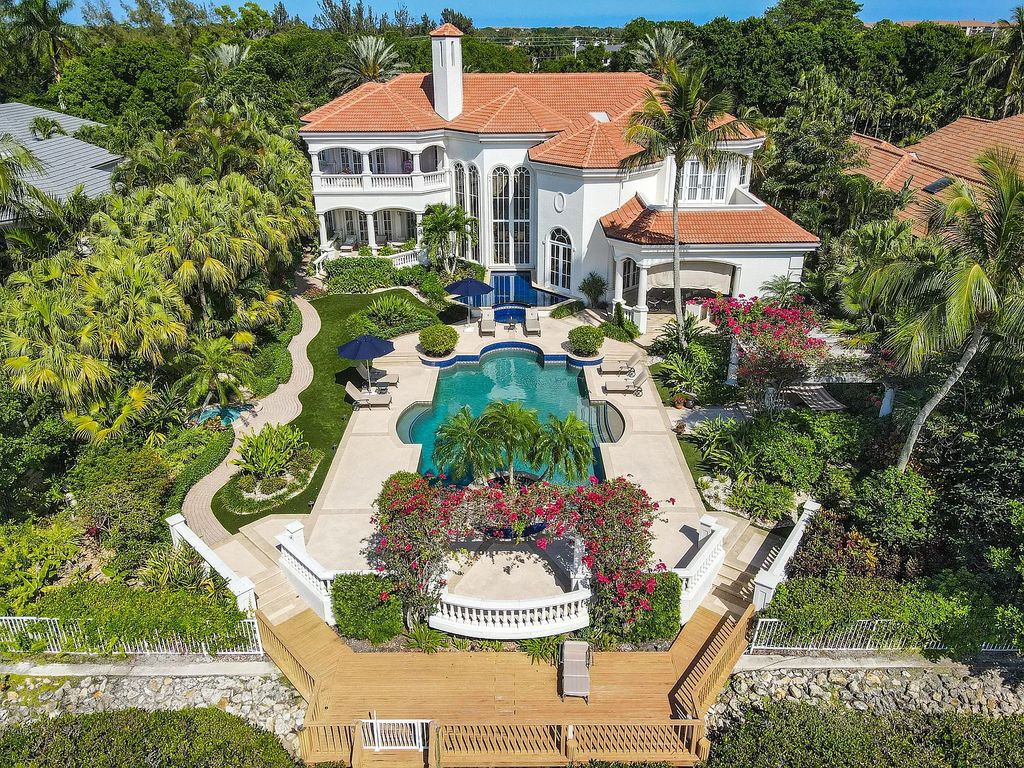 Outstanding custom estate located at 456 Mariner Dr, Jupiter, Florida, in the exclusive guard-gated community of Admirals Cove. It sits on 110' of waterfrontage with no fixed bridges. This timeless masterpiece features 5 BR/5.1 BA + an office, boasting 9,101 sq ft with soaring ceilings and spectacular water views from almost every room.