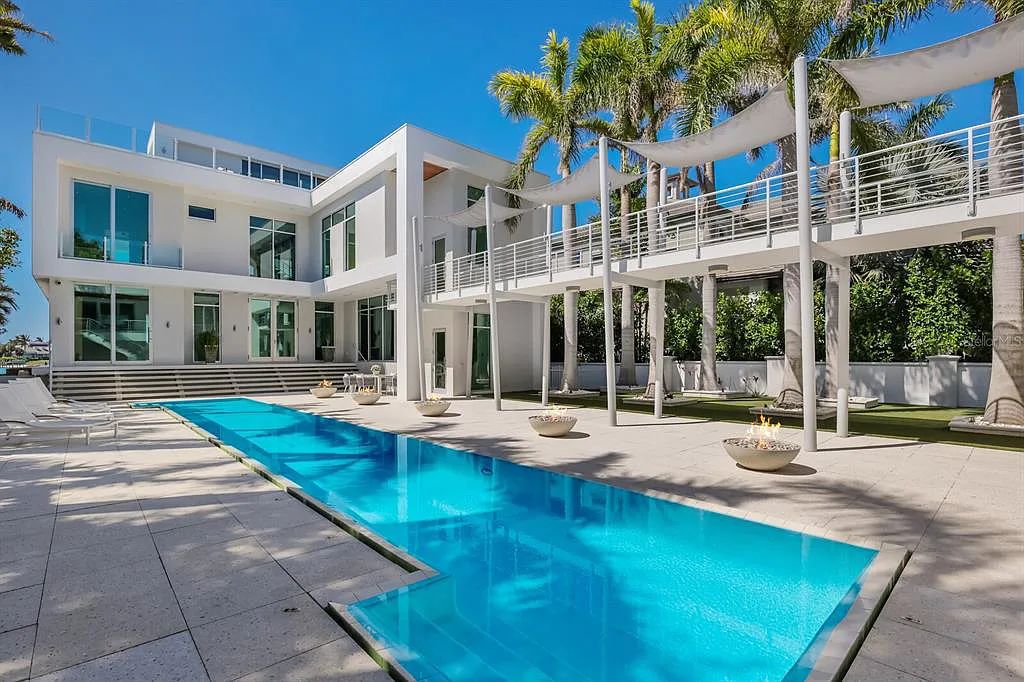 1325 Westway Dr, Sarasota, FL - A modern marvel overlooking New Pass in Lido Shores! Step into this tropical escape through the hidden courtyard that connects the three-bedroom main home to the secluded, two-bedroom guest house. The property features an expansive sundeck, a 60-foot wet-edge lap pool lined with royal palms and adorned with unique fire bowls. This serves as the perfect introduction to a contemporary masterpiece designed by DSDG Architect Mark Sultana and built by Voigt Brothers Construction.