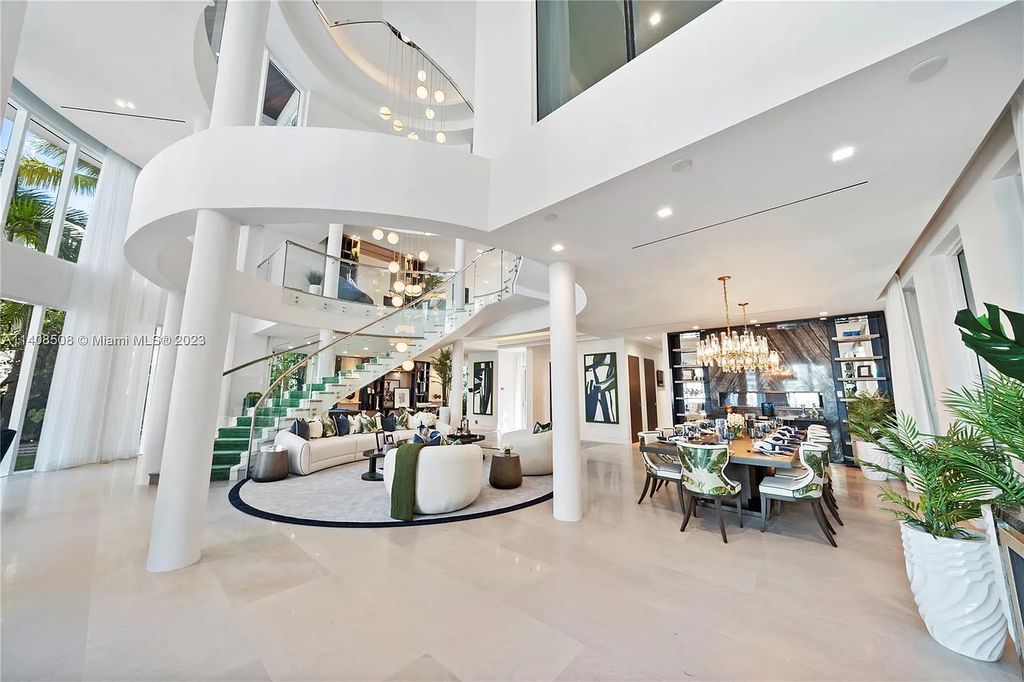 5785 Pine Tree Drive, Miami Beach, Florida, is a new Neo-Classic, one-of-a-kind, three-story waterfront home. It is fully furnished, equipped, and adorned by Argent Design. The house features an open atrium entry with water features and glass, as well as a stunning circular glass centerpiece staircase that stands 30 feet tall with a curved handrail. The living area spans an impressive 15,000 square feet, offering eight bedrooms, six full bathrooms, and two half bathrooms. The kitchen boasts large touch sensor cabinets.