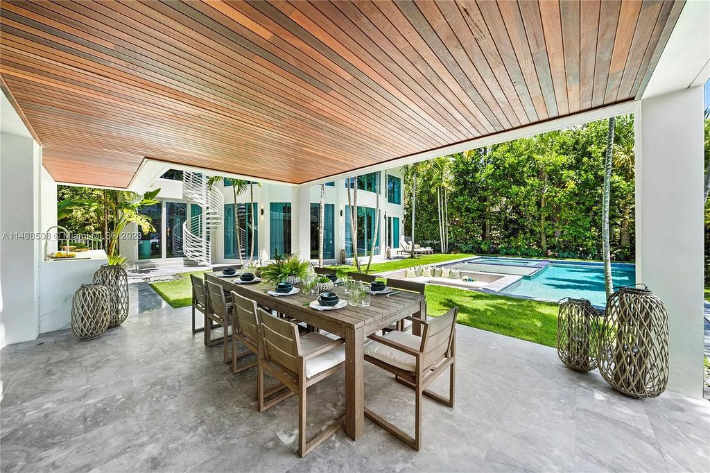 5785 Pine Tree Drive, Miami Beach, Florida, is a new Neo-Classic, one-of-a-kind, three-story waterfront home. It is fully furnished, equipped, and adorned by Argent Design. The house features an open atrium entry with water features and glass, as well as a stunning circular glass centerpiece staircase that stands 30 feet tall with a curved handrail. The living area spans an impressive 15,000 square feet, offering eight bedrooms, six full bathrooms, and two half bathrooms. The kitchen boasts large touch sensor cabinets.