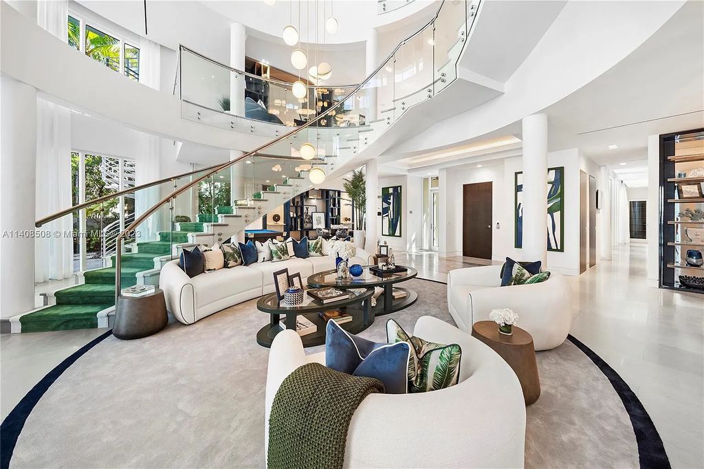 5785 Pine Tree Drive, Miami Beach, Florida, is a new Neo-Classic, one-of-a-kind, three-story waterfront home. It is fully furnished, equipped, and adorned by Argent Design. The house features an open atrium entry with water features and glass, as well as a stunning circular glass centerpiece staircase that stands 30 feet tall with a curved handrail. The living area spans an impressive 15,000 square feet, offering eight bedrooms, six full bathrooms, and two half bathrooms. The kitchen boasts large touch sensor cabinets.