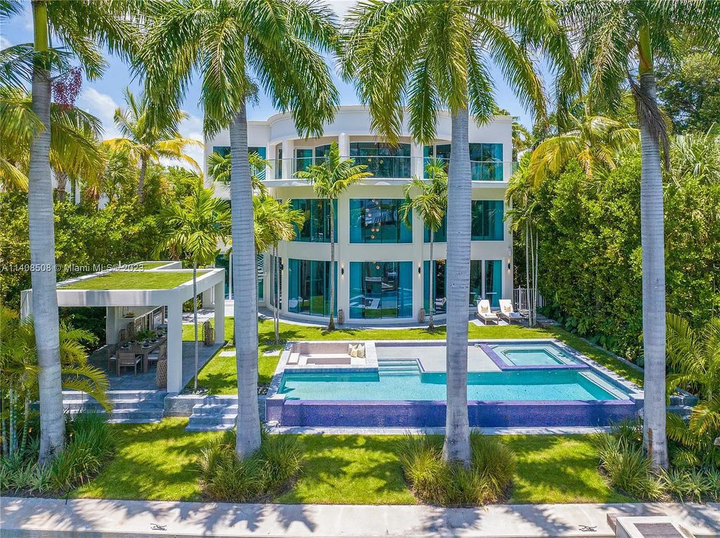 5785 Pine Tree Drive, Miami Beach, Florida, is a new Neo-Classic, one-of-a-kind, three-story waterfront home. It is fully furnished, equipped, and adorned by Argent Design. The house features an open atrium entry with water features and glass, as well as a stunning circular glass centerpiece staircase that stands 30 feet tall with a curved handrail. The living area spans an impressive 15,000 square feet, offering eight bedrooms, six full bathrooms, and two half bathrooms. The kitchen boasts large touch sensor cabinets.