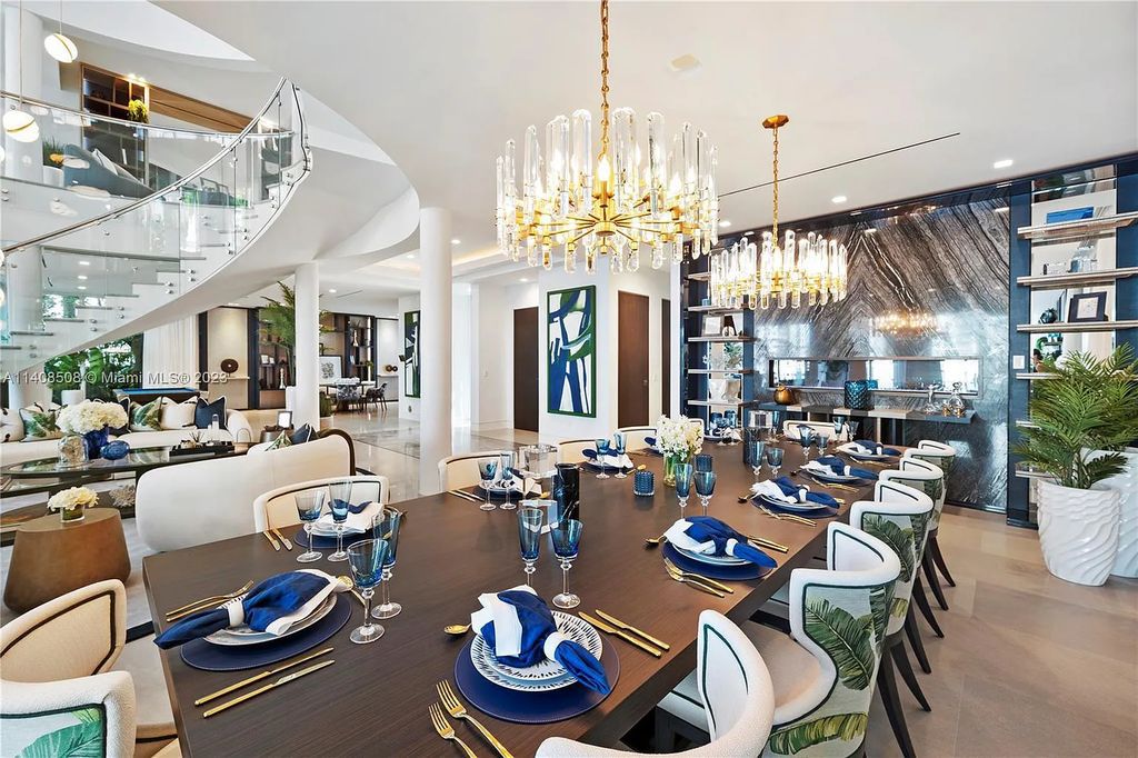 5785 Pine Tree Drive, Miami Beach, Florida, is a new Neo-Classic, one-of-a-kind, three-story waterfront home. It is fully furnished, equipped, and adorned by Argent Design. The house features an open atrium entry with water features and glass, as well as a stunning circular glass centerpiece staircase that stands 30 feet tall with a curved handrail. The living area spans an impressive 15,000 square feet, offering eight bedrooms, six full bathrooms, and two half bathrooms. The kitchen boasts large touch sensor cabinets.