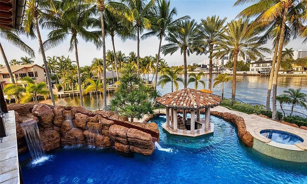 Located at 2900 NE 37th St, Fort Lauderdale, Florida, this gated palatial Palm Beach-inspired point estate is situated in the prestigious Coral Ridge Country Club enclave, spanning over 1.09 acres (+/-) and surrounded by three astonishing sides of wrap-around waterfront, amounting to an impressive 665 feet (+/-) of full-service mega-yacht dockage.