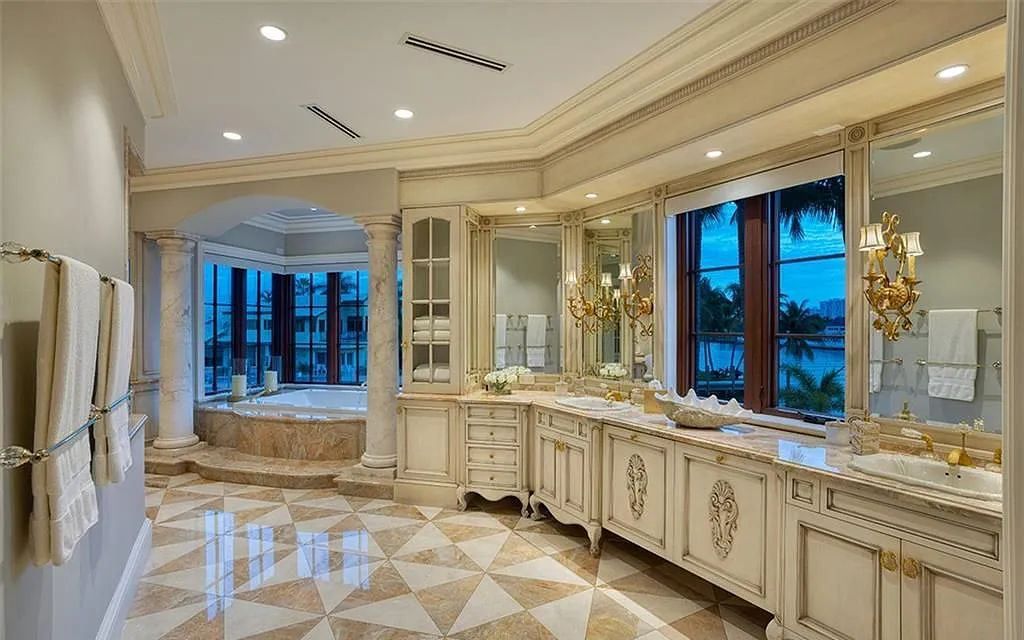 Located at 2900 NE 37th St, Fort Lauderdale, Florida, this gated palatial Palm Beach-inspired point estate is situated in the prestigious Coral Ridge Country Club enclave, spanning over 1.09 acres (+/-) and surrounded by three astonishing sides of wrap-around waterfront, amounting to an impressive 665 feet (+/-) of full-service mega-yacht dockage.