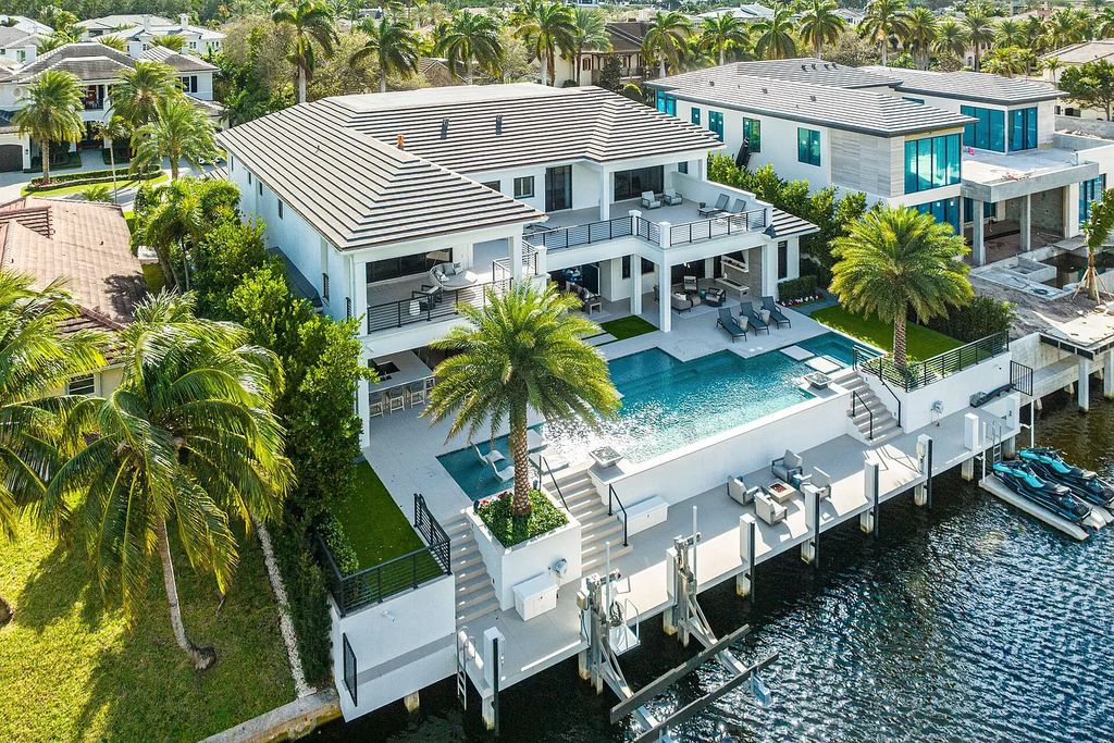 Set sail from your backyard in this custom 5-bedroom waterfront estate by SRD Building Corp. Luxurious living awaits with resort-style pool, dock, chef's kitchen, & smart home features. Explore 215 W Coconut Palm Rd, Boca Raton.